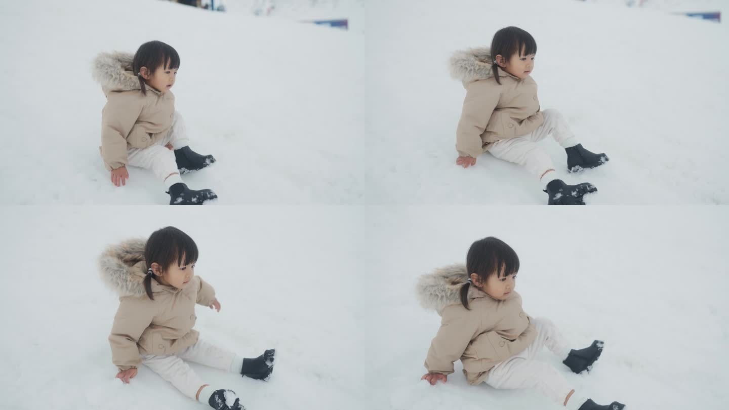 小女孩穿着暖和的冬衣，兴奋地在雪地上坐着，动着。