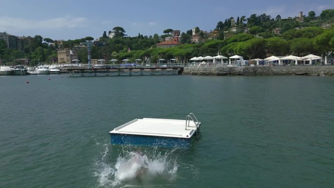 意大利利古里亚，一名少年在海上的浮动平台上玩耍的无人机画面