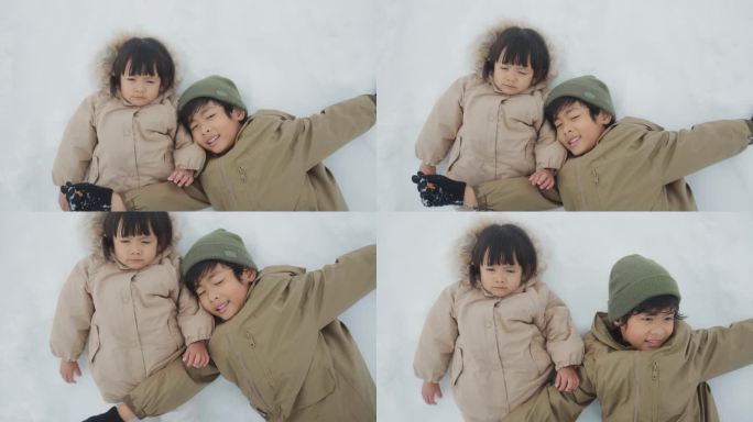 可爱的小男孩和小女孩躺在雪地里看着镜头。