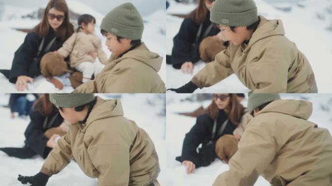 一群家人坐在雪地上，一个男孩在冬天为妹妹堆雪人。