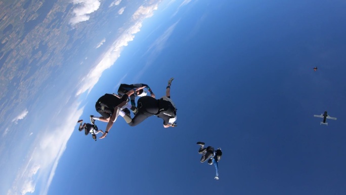 在阳光明媚的日子里，跳伞者在自由落体时表演杂技