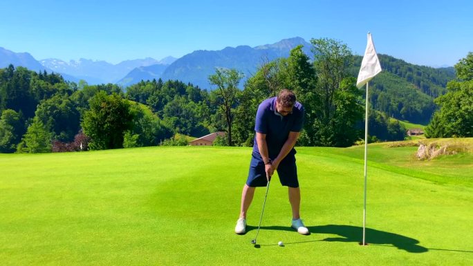 高尔夫球手将球靠近球洞的山景和阳光下的皮拉图斯山峰