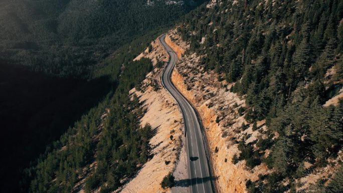 蜿蜒的道路在绿色的森林在山上。无人机航拍图