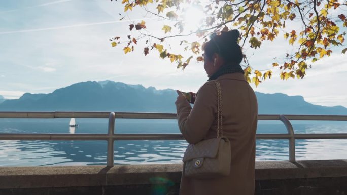 快乐的亚洲女人与美丽的秋天的法国春天的Annecy湖在瑞士沃韦的春天的Annecy湖聊天