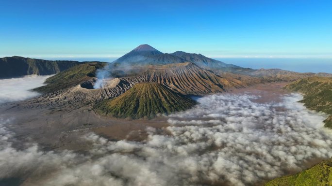 空中无人机拍摄的印尼爪哇岛东爪哇岛腾格里火山口喷发火山Bromo火山的日出场景，周围有云、雾和烟，还