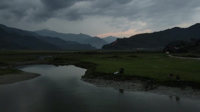 无人机飞越费瓦湖，一名妇女在船上钓鱼，在博卡拉欣赏尼泊尔山谷美景。