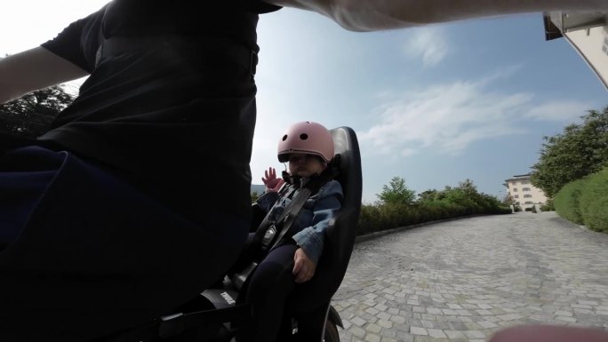 宝宝坐在自行车后座的婴儿座椅上，骑在宁静的乡间小路上，穿越大自然
