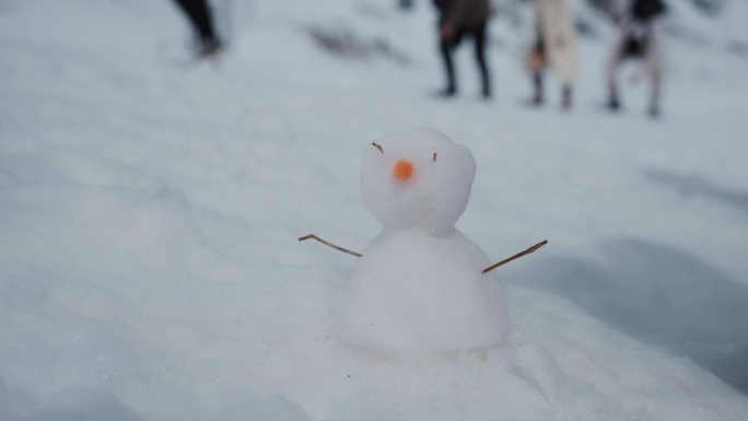 可爱的雪人的特写肖像在一个人的背景在山上。