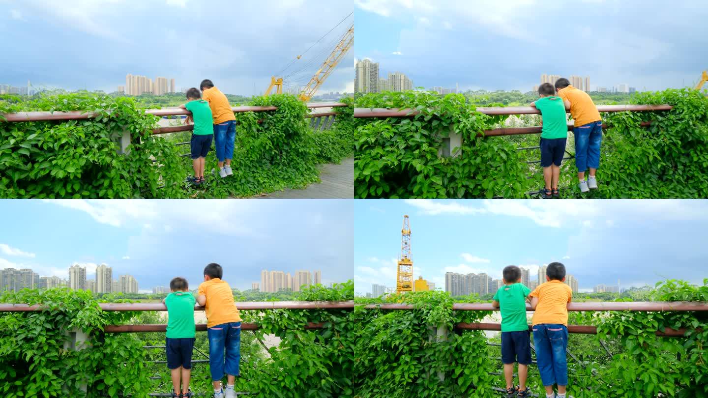 两个小孩在江边爬栏杆看风景