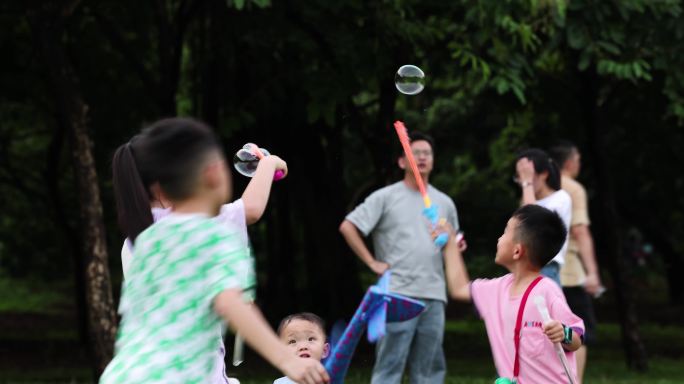 公园玩泡泡机的小孩子