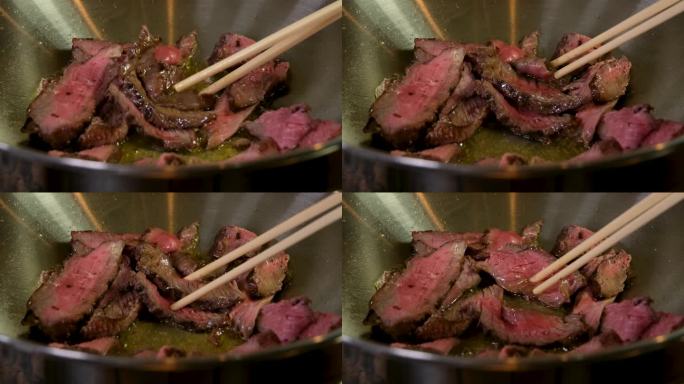 用葵花籽橄榄油煎肉，用东方筷子翻面，开始烹饪东方料理粉丝炒锅各种美味的肉类菜肴，视频肉配血粉色软牛肉