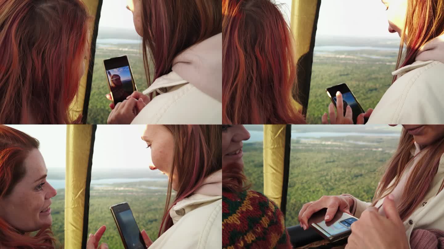 两个女孩乘坐热气球飞行，其中一个给另一个看她用智能手机拍的人像照片