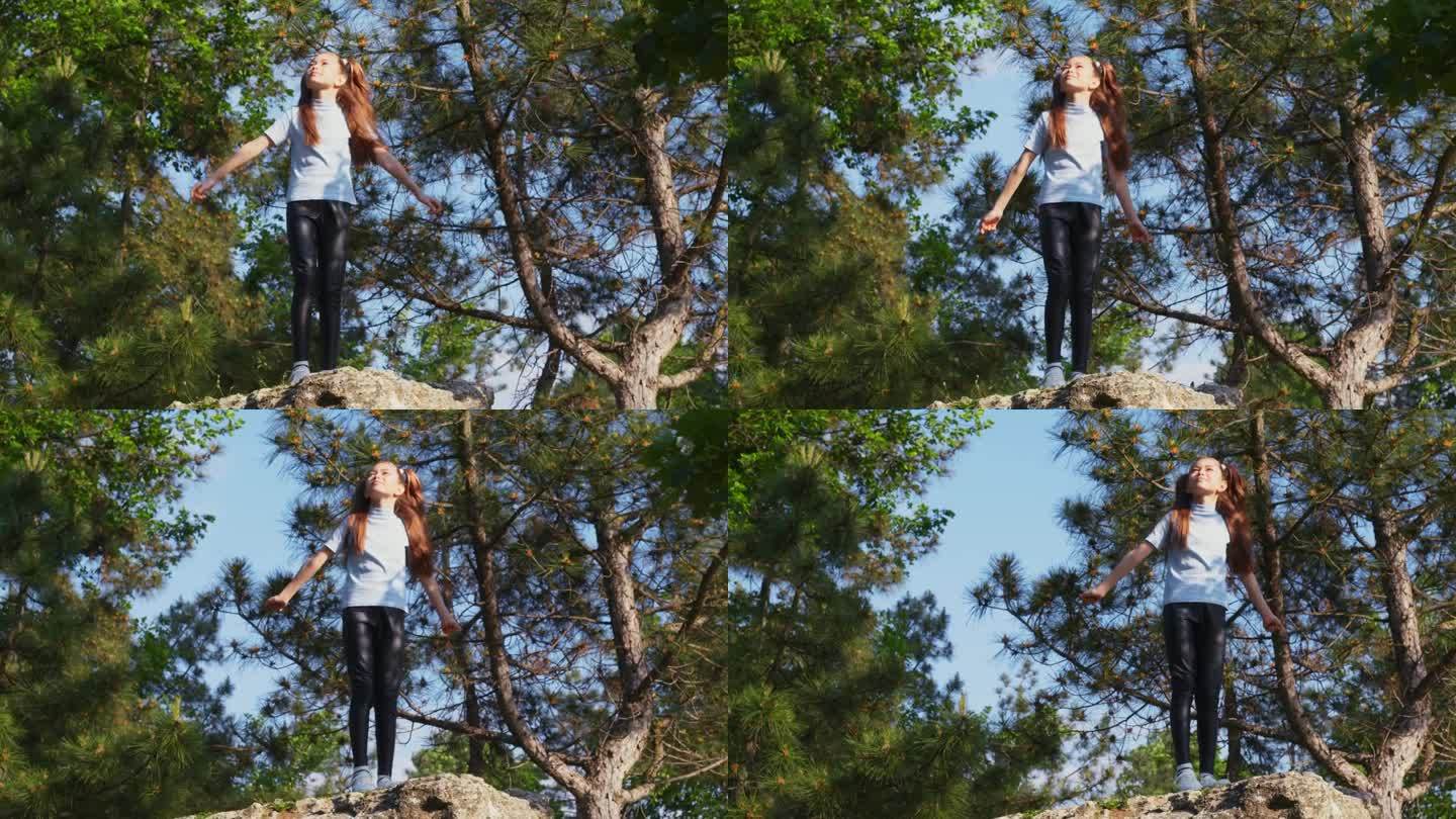 小女孩站在森林中央的一块石头上，举起双臂