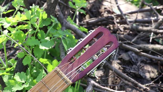 一个古老的吉他矗立在公园的草地上，在夏天的阳光下，在乌克兰，一个乐器