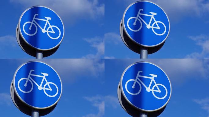 圆形道路标志，蓝色背景白色自行车，蓝色天空背景下的自行车专用道。自行车道杆上的蓝色圆形标志