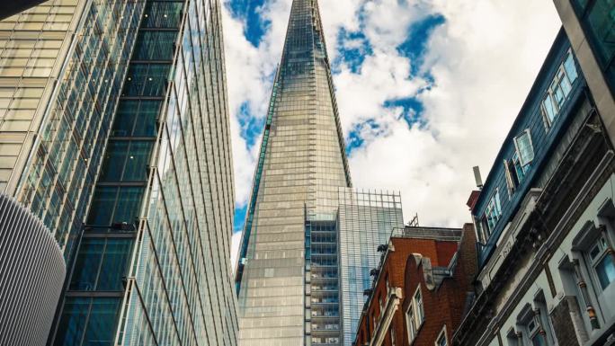 低角度拍摄的高耸的公司大楼摩天大楼，云层在高耸的建筑和玻璃建筑中反射，英国伦敦