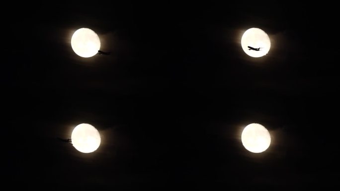 在明亮的满月背景下，一架飞行中的客机在夜空中的剪影，4k慢动作镜头。