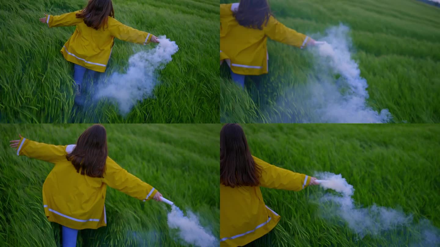 年轻女子拿着白烟火炬跑过绿色的麦田
