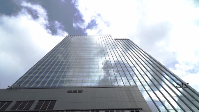 在蓝色晴朗的天空背景下，高层玻璃建筑和深色钢窗系统的景色。未来建筑的经营理念，仰望着楼顶的阳光