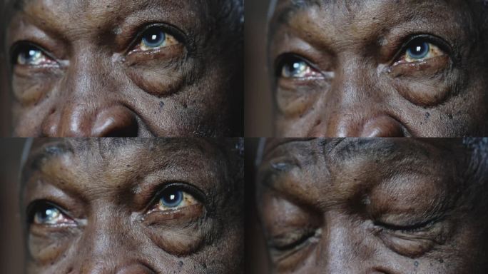 一个黑人老人满怀希望地向上凝视着，微距特写的细节是老人布满皱纹的眼睛。闭上眼睛沉思和思考的非裔美国人