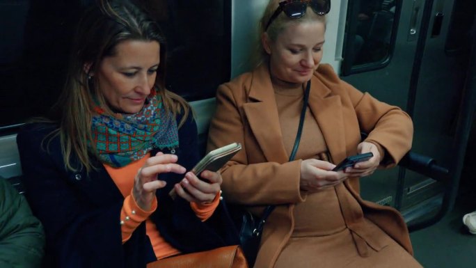 两名女子在乘坐地铁时使用智能手机