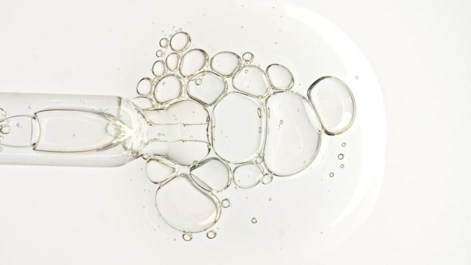 透明的化妆品凝胶液，血清与分子气泡油在移液管滴在一个白色的背景。天然有机化妆品、药品微距拍摄。生产特