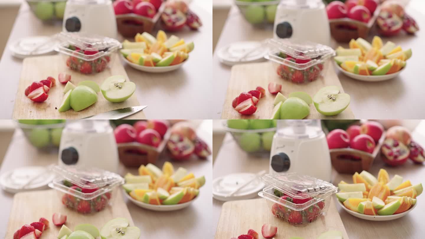 木桌上摆放着各种各样的水果。果汁搅拌机里的水果原料。作为健康奶昔原料的水果:苹果、草莓和石榴。