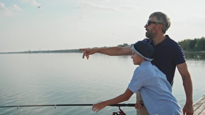 一个成熟的男人和他的儿子在夏天钓鱼