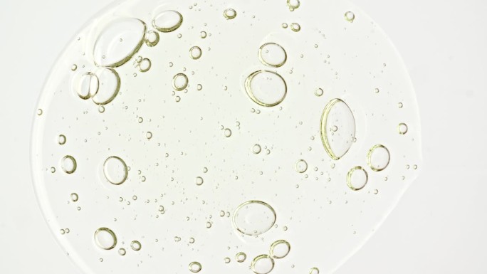 透明的化妆品凝胶流体与分子气泡油分布在白色的背景。天然有机化妆品、药品微距拍摄。生产特写。慢动作