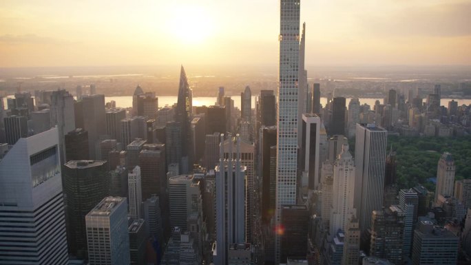 傍晚纽约市空中景观与曼哈顿中城摩天大楼和绿色自然在中央公园。城市天际线的电影无人机视图与风景秀丽的日