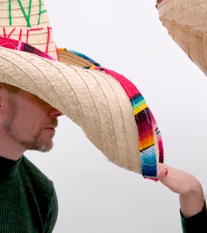 男人和女人戴着墨西哥宽边帽，互相顶着大帽檐，笑着享受生活，恋爱关系，糖果花时期的乐趣