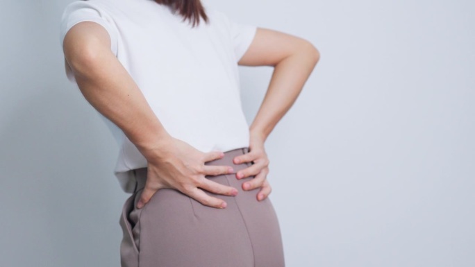 灰色背景为肌肉疼痛的成年女性。因梨状肌综合征、腰痛和脊柱受压而腰痛的老年妇女。办公室综合症与医学概念