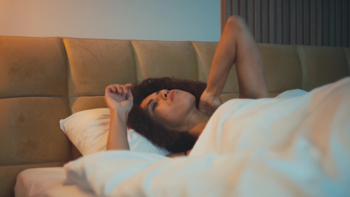 困扰的非裔美国妇女感到颈部疼痛，躺在不舒服的枕头上