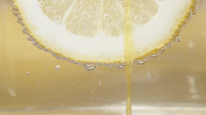 柠檬片，泡在柠檬水里。蜂蜜顺着它流下来。特写慢镜头。