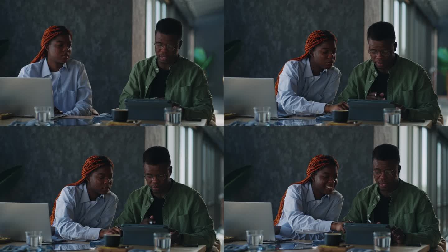 一位非洲裔美国男女拿着咖啡杯和笔记本电脑在咖啡馆里进行商务交流