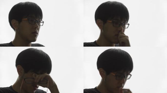 悲伤的年轻亚洲男子取下眼镜并重新戴上