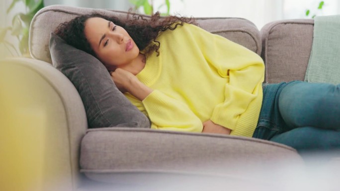 胃部疼痛，有消化问题或经前综合症的女性坐在沙发上。肚子，病毒和生病的女性便秘，肿胀或子宫内膜异位症在