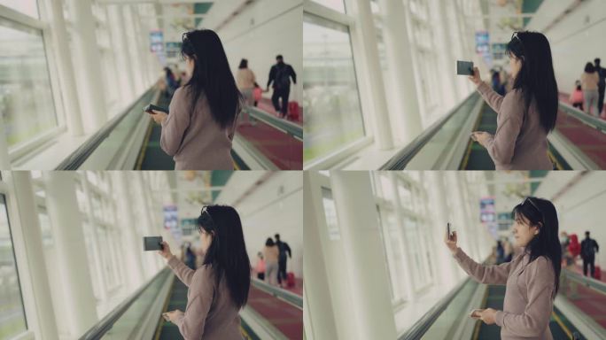 一位女商人隔着机场的玻璃墙，用智能手机拍摄日落