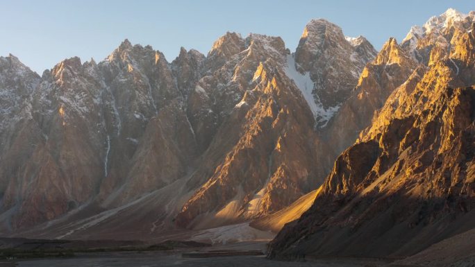 在巴基斯坦北部罕萨山谷地区的帕苏山谷的春天，喀喇昆仑山脉雪山的壮丽景色的延时移动光影日落场景