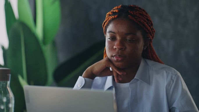 咖啡馆文化:一位黑人女性在一家时髦的咖啡馆里工作，一边用笔记本电脑工作，一边享受着这里的氛围