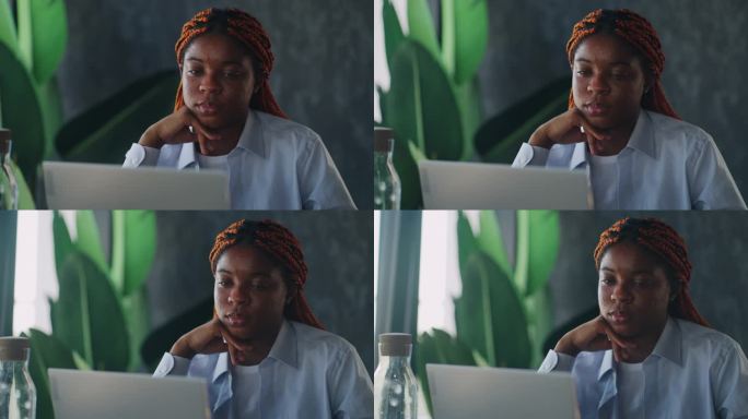 咖啡馆文化:一位黑人女性在一家时髦的咖啡馆里工作，一边用笔记本电脑工作，一边享受着这里的氛围