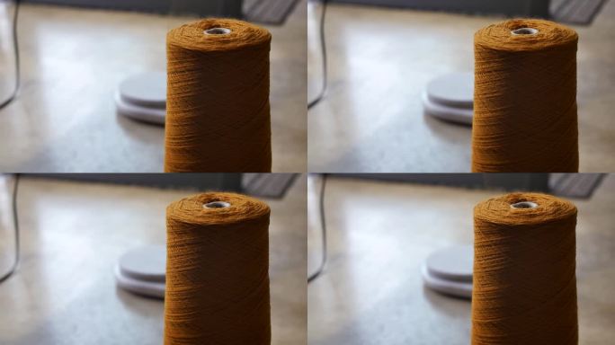 细节:一大块橙色纱线，有一根向上伸展的开卷线。用姜黄色纱线把毛线卷开的过程。羊毛生产