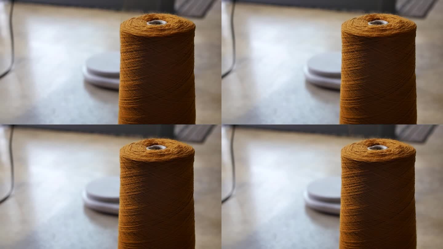 细节:一大块橙色纱线，有一根向上伸展的开卷线。用姜黄色纱线把毛线卷开的过程。羊毛生产