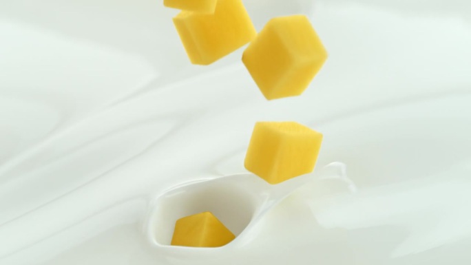 芒果块落入奶油牛奶中，在微距和慢镜头中产生漩涡飞溅