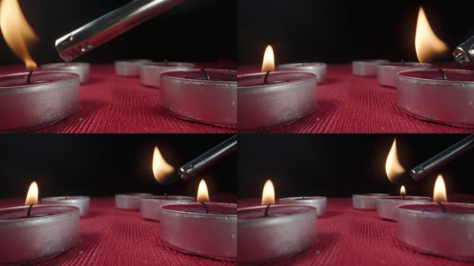我轮流点燃红色桌布上的红色蜡烛。极端特写镜头。