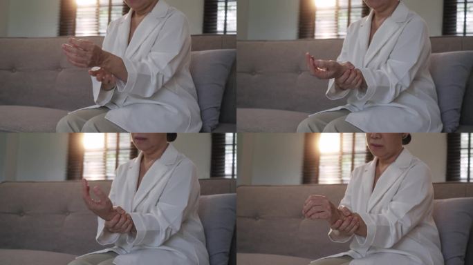 60多岁的亚洲女性按摩自己的手腕，感觉关节疼痛和肿胀。