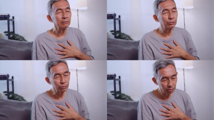 一位亚洲老人坐在家里的沙发上呼吸困难。