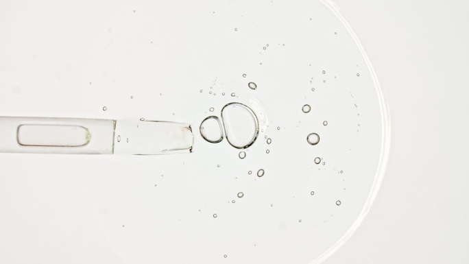 透明的化妆品凝胶流体与分子气泡油分布在白色的背景。天然有机化妆品、药品微距拍摄。生产特写。慢动作