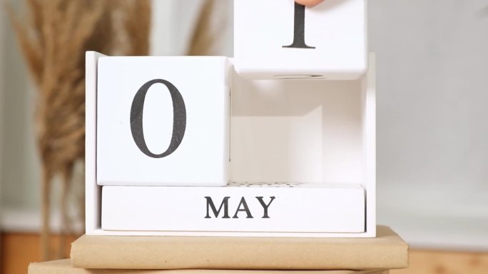 这个人把日期写在日历上5月1日。5月1日。桌上放着五一木制日历。春季的一天