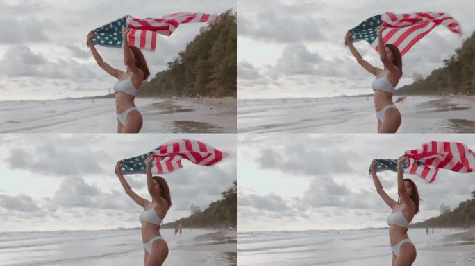 7月4日独立纪念日，年轻的亚洲女子在海滩上享受时光，在日落的天空下，在夏天的海滩上挥舞着美国国旗。
